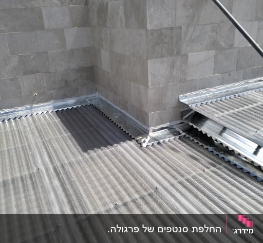 גג מתכת גלי ליד קיר אבן
